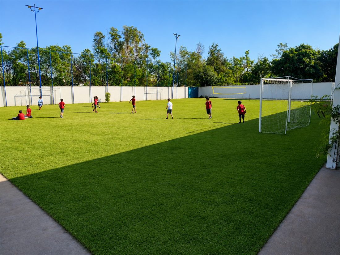Alunos jogando futebol no campo gramado