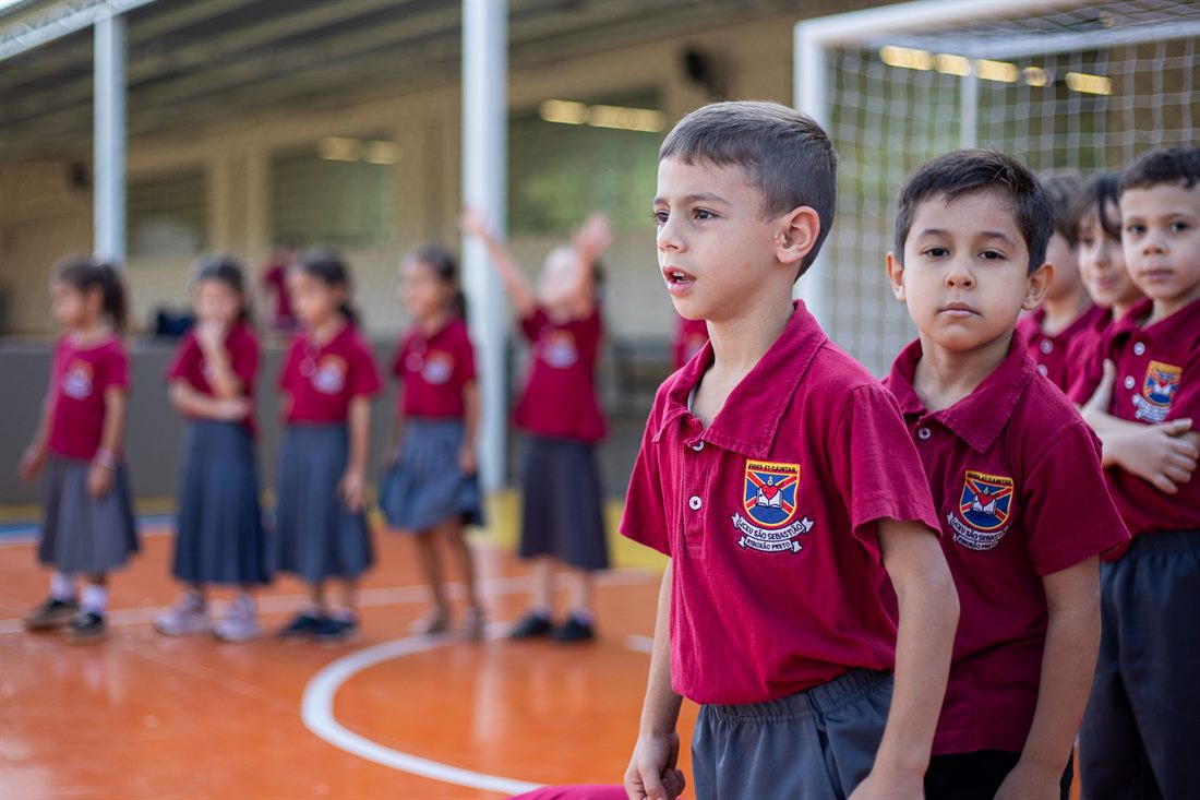 Alunos em fila na quadra, no início da aula de educação física