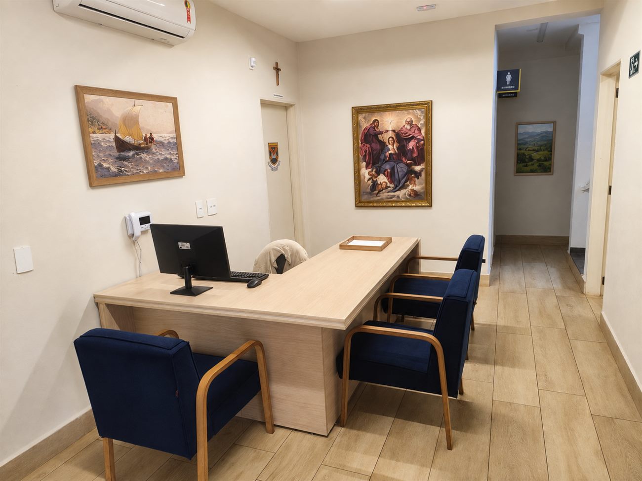 Secretaria do colégio, com mesa de atendimento e poltronas para as famílias